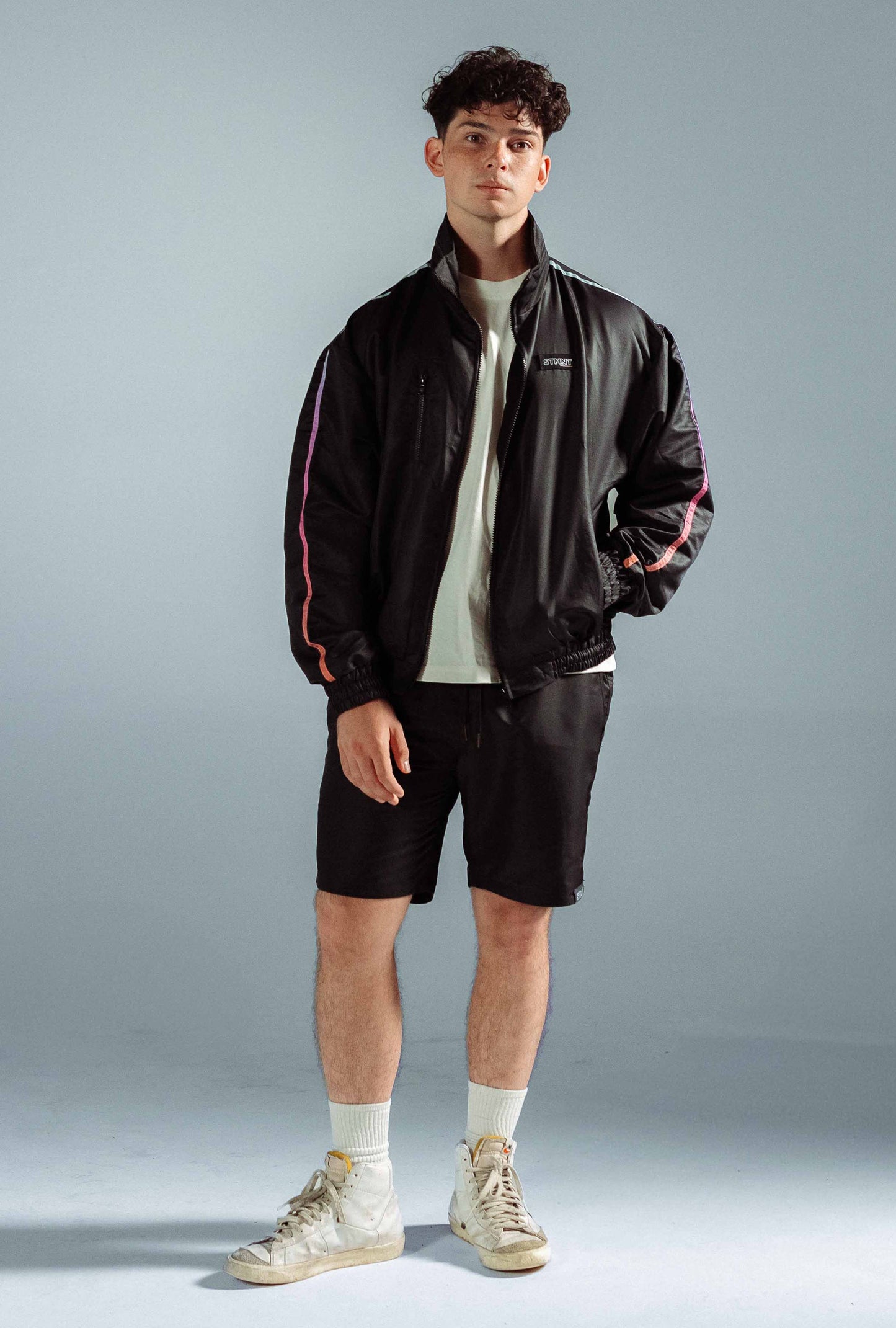 STMNT Wear Black First Edition Full Tracksuit - open track jacket with gradient orange-blue stripe over white tee and shorts, full-length studio shot