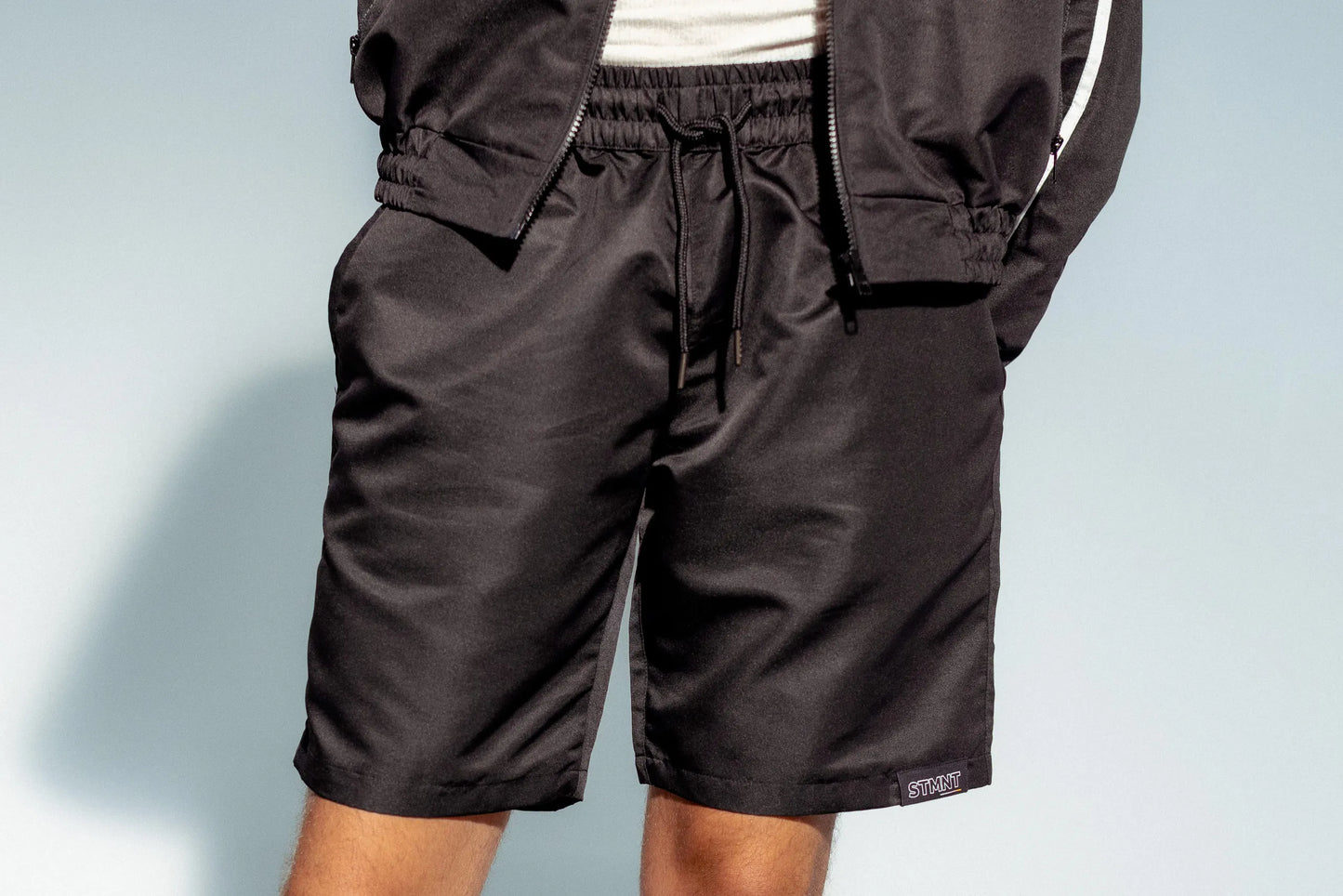 STMNT Wear black drawstring athletic shorts detail showing elastic waist and logo patch