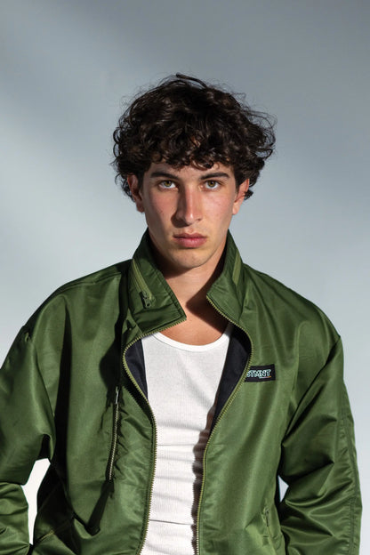 STMNT Wear Green Full Tracksuit - olive track jacket with STMNT chest logo over white tee, portrait closeup studio shot