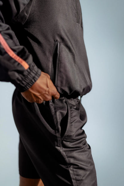 STMNT Wear First Edition Black Full Kit detail - side zip pocket closeup on track jacket showing orange accent piping